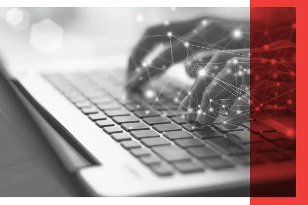 Black and white image of hands typing on laptop with red overlay