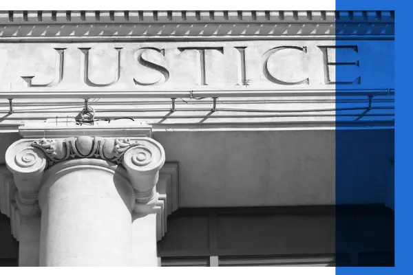 Black and white image of a courthouse exterior displaying the word 'justice'