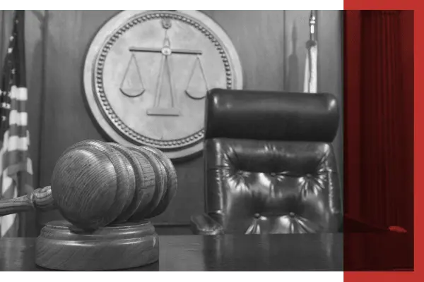 Black and white image of gavel and chair at judge bench in courtroom