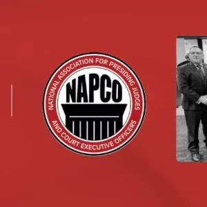 A red banner with the For The Record and NAPCO logos and an image of four men standing at a conference booth.