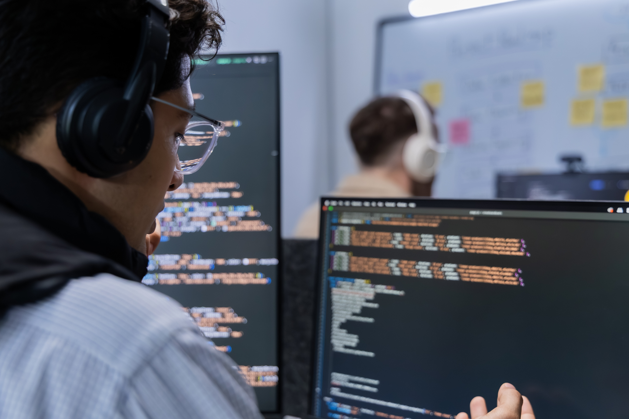 Two male software developers sitting at computer screens